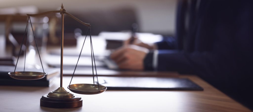 Scales of justice and blurred lawyer on background